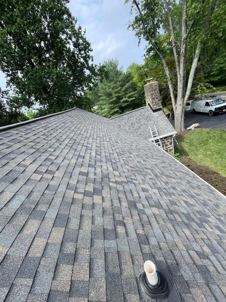 Plumbing vent pipe boot and stone chimney on an architectural shingle roof in Bucks County, PA